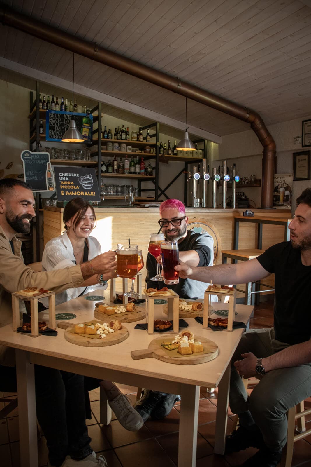 Quattro ragazzi brindano durante un aperitivo alla Quercia