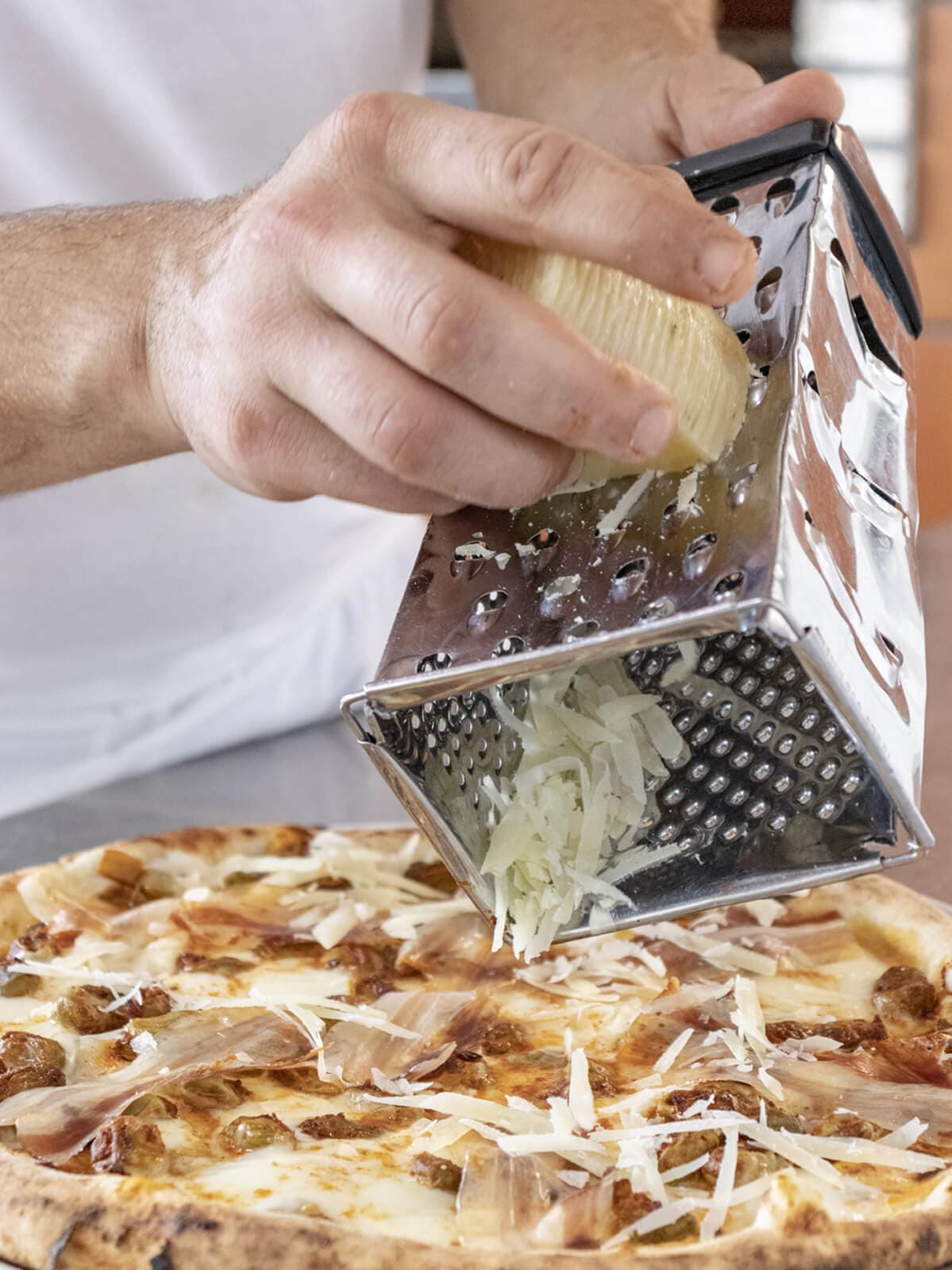 Pizza che viene condita con del pecorino